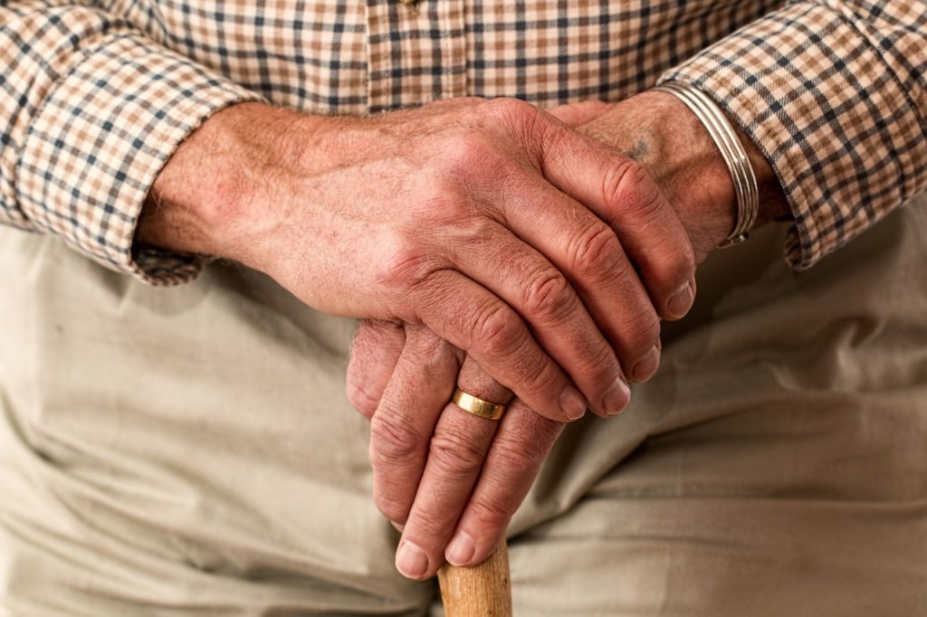 Old man's hands over walking cane