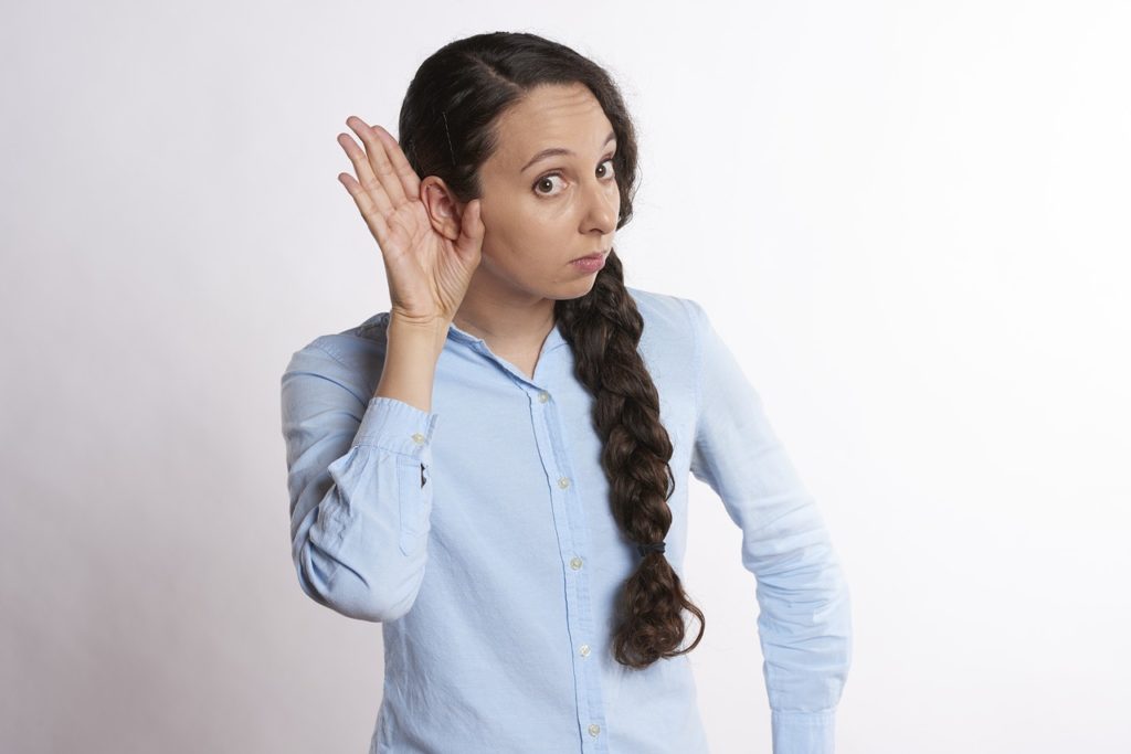 Woman with hand to her ear, listening
