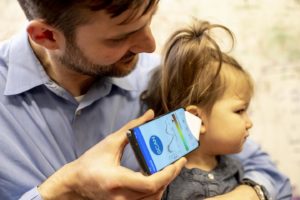 A parent uses the app and funnel to check his daughter's ear. Image courtesy of Dennis Wise/University of Washington.