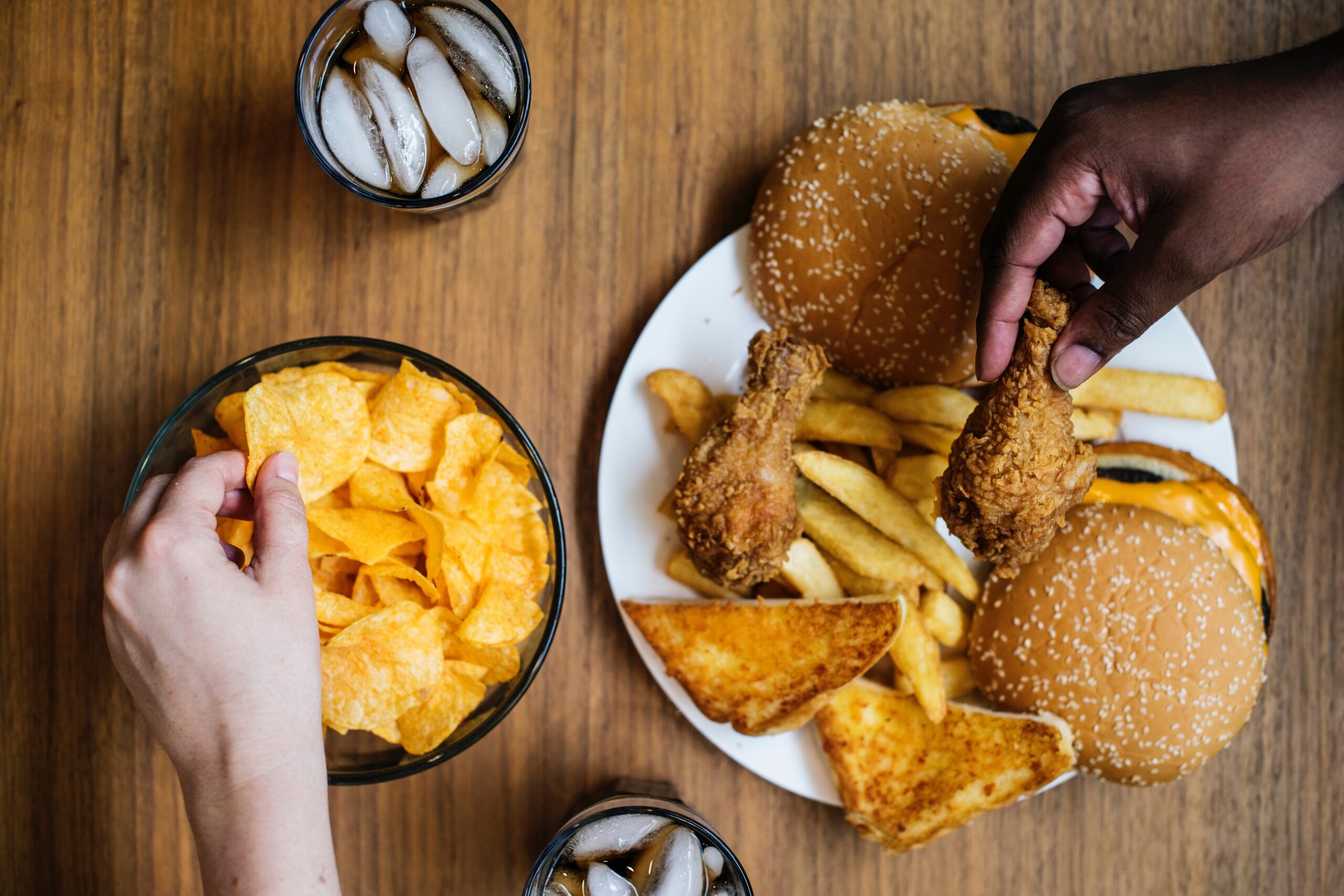 People grabbing chips and fried chicken