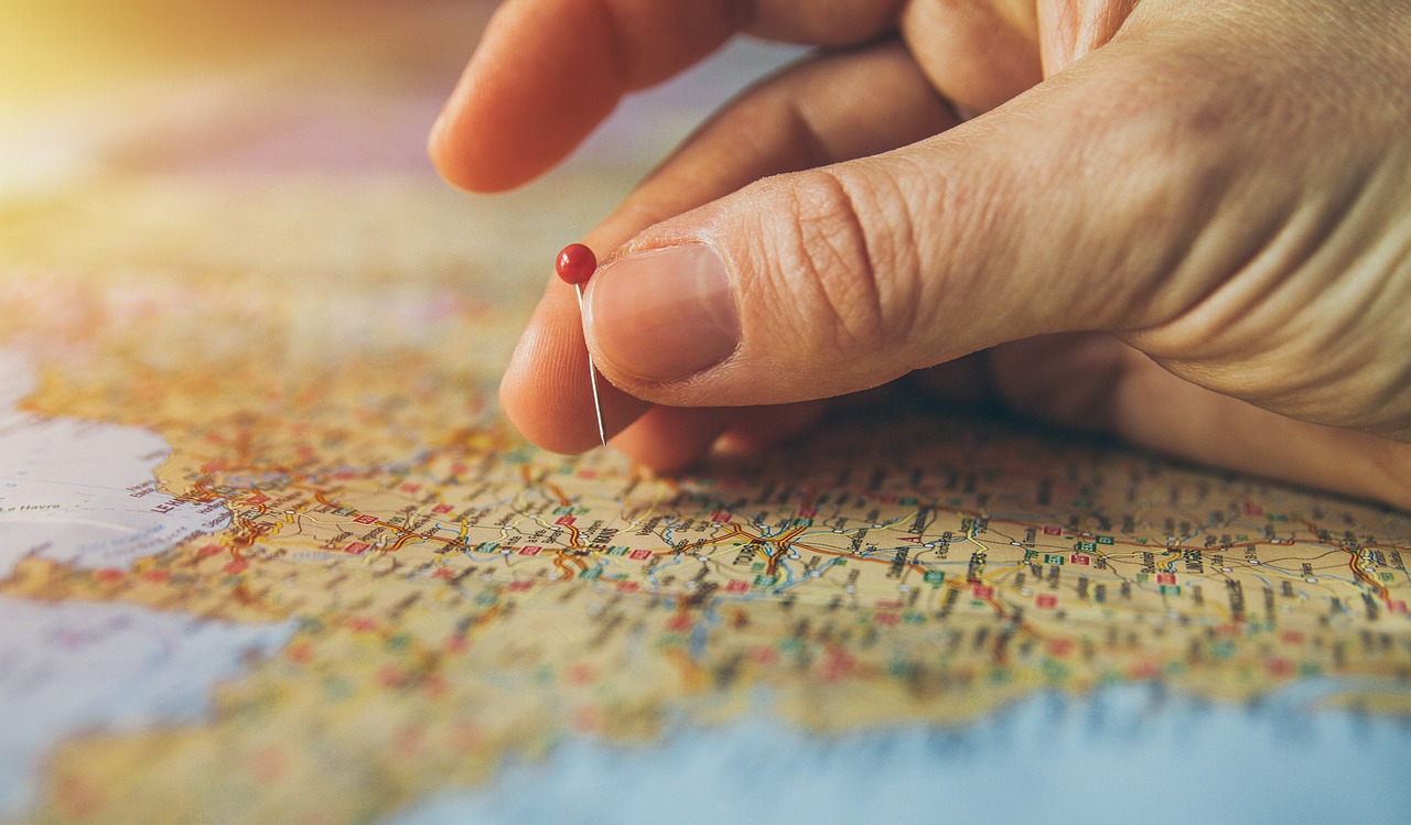 Hand pushing pin into world map